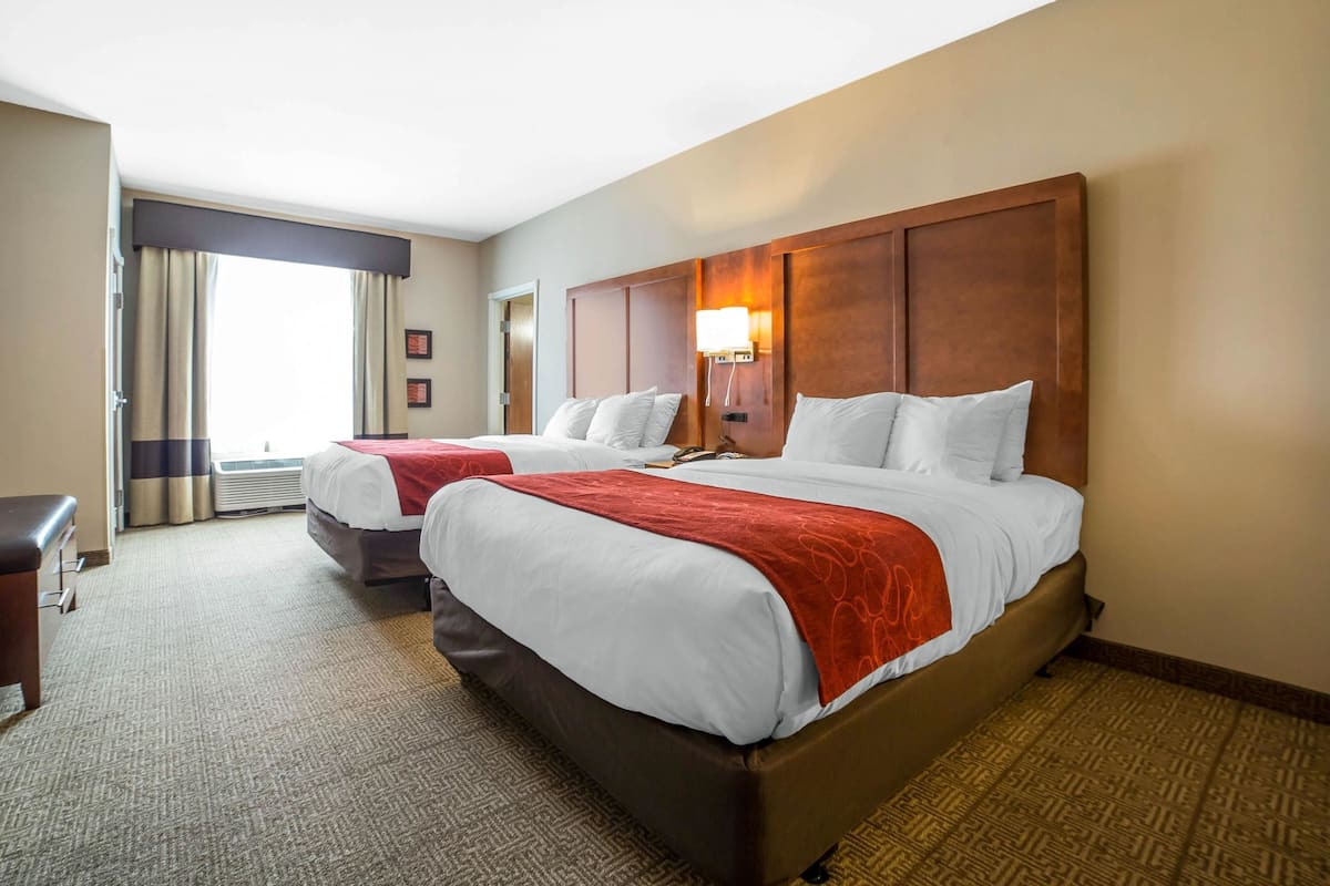 Habitación de hotel con dos camas, un escritorio y una ventana con cortinas.