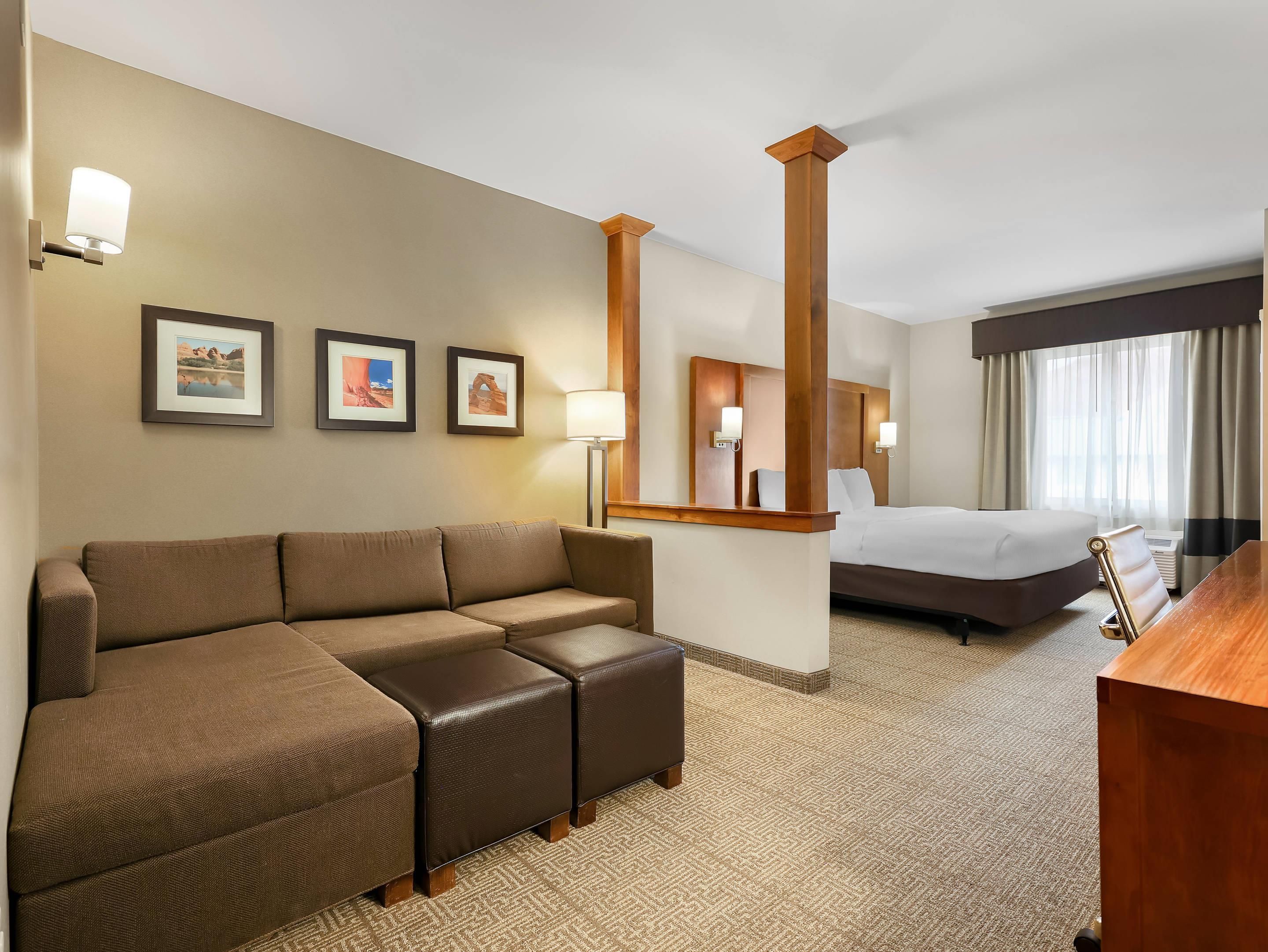 A hotel room with a sofa, a bed, a desk, and a mirror.