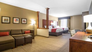 Una habitación de hotel con sofá, dos camas, escritorio y cuadros en la pared.