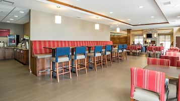 A spacious hotel lobby with a bar area, seating arrangements, and a fireplace.