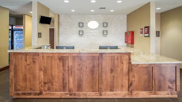 A reception area with a wooden counter, a TV mounted on the wall, and a sign that reads "Comfort Suites."