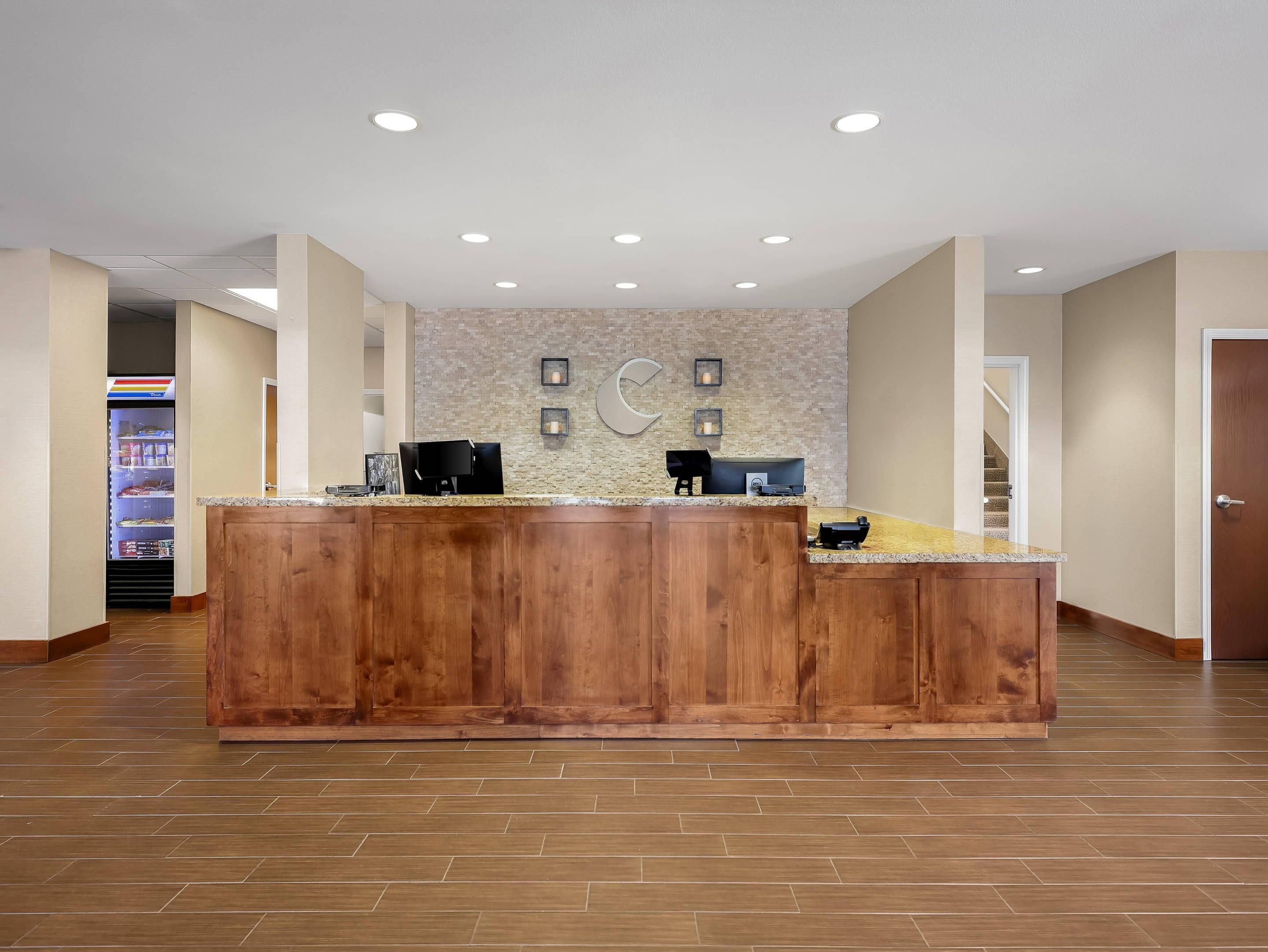 A reception desk with a wooden finish, a stone wall with framed pictures, and a tiled floor.