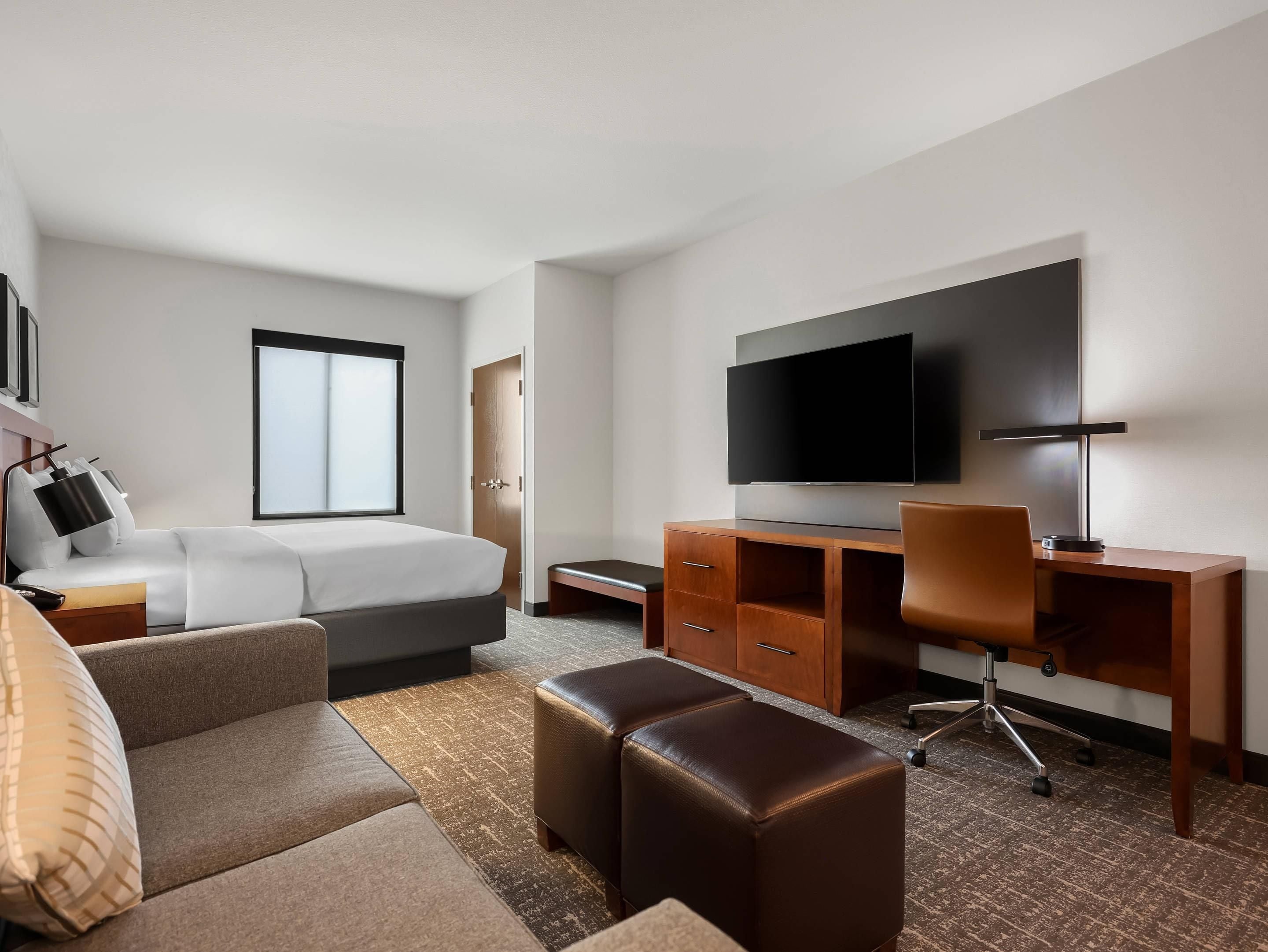 Une chambre d’hôtel équipée d’un lit, d’un bureau, d’une chaise, d’une télévision et d’une fenêtre.