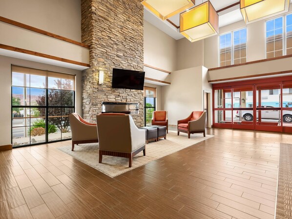 Un vestíbulo amplio con pared de piedra, asientos cómodos, un televisor de pantalla plana y ventanas grandes que ofrecen vistas al exterior.
