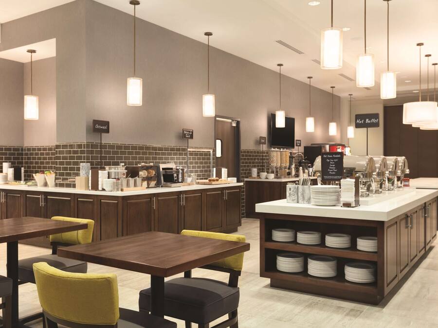 A modern restaurant with a central island, multiple seating areas, and a buffet section.