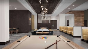 Une table de billard avec des billes et des queues, un espace détente avec des chaises et une table.