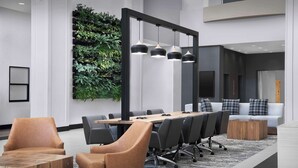 Une salle de conférence moderne, dotée d’une longue table, de fauteuils en cuir et d’un système d’éclairage suspendu.