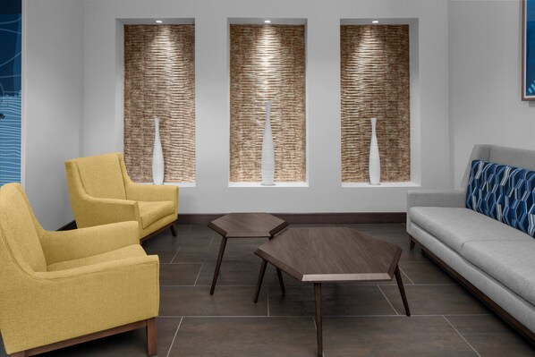 A modern waiting area with yellow chairs, a grey sofa, and a wooden coffee table. - Holiday Inn Express & Suites Midland South I-20 by IHG (Midland)