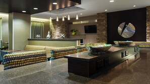 A modern interior with a seating area, a kitchen counter, and a decorative wall. - Holiday Inn Express & Suites Midland South I-20 by IHG (Midland)