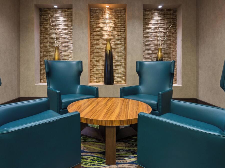 A room with a round wooden table surrounded by four blue chairs, two on each side.