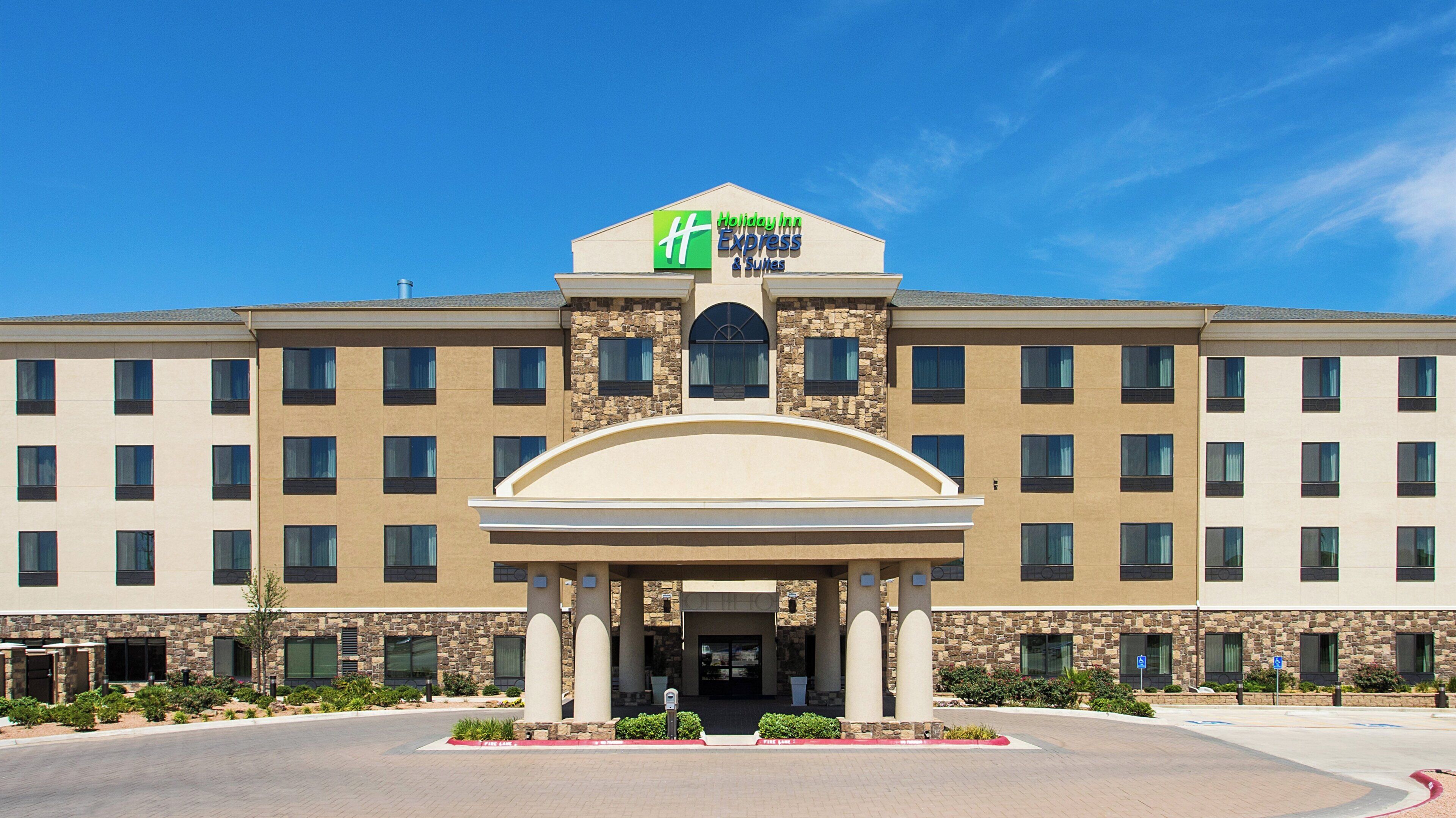 Un hotel Holiday Inn Express & Suites con fachada de piedra, múltiples ventanas y entrada cubierta.
