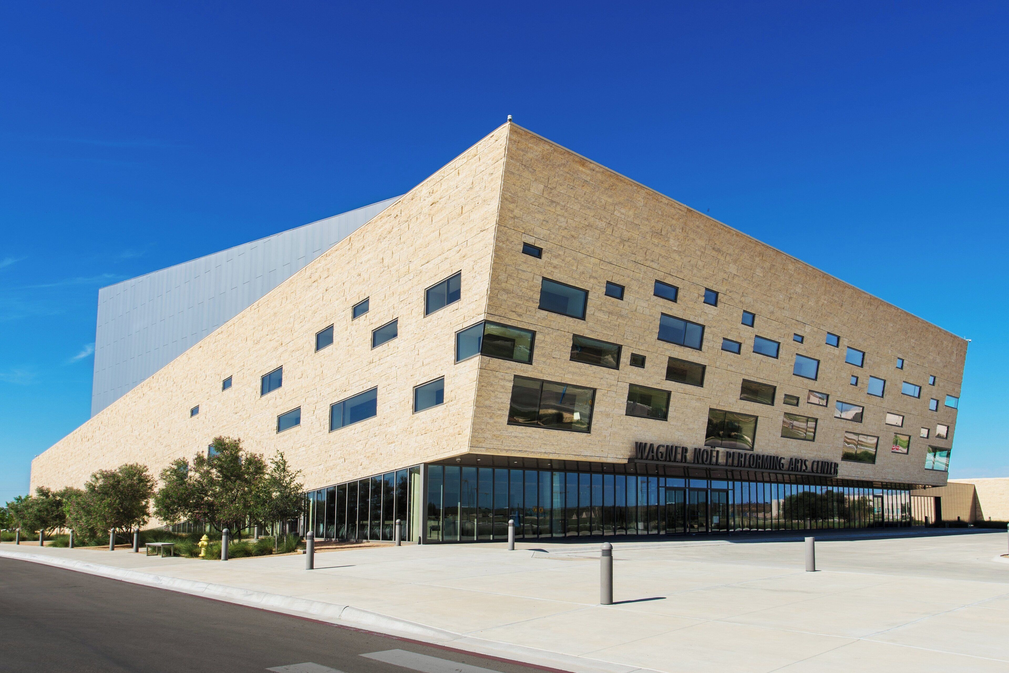 Un bâtiment moderne doté d’un toit plat, de nombreuses fenêtres et surplombant un ciel dégagé.