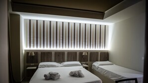 A hotel room with a large bed, two bedside tables, a nightstand, and a headboard with vertical slats. - Hotel Cliché (San Lucido)
