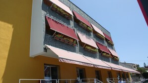 A hotel with multiple balconies, each with red awnings and flower boxes. - Hotel Cliché (San Lucido)