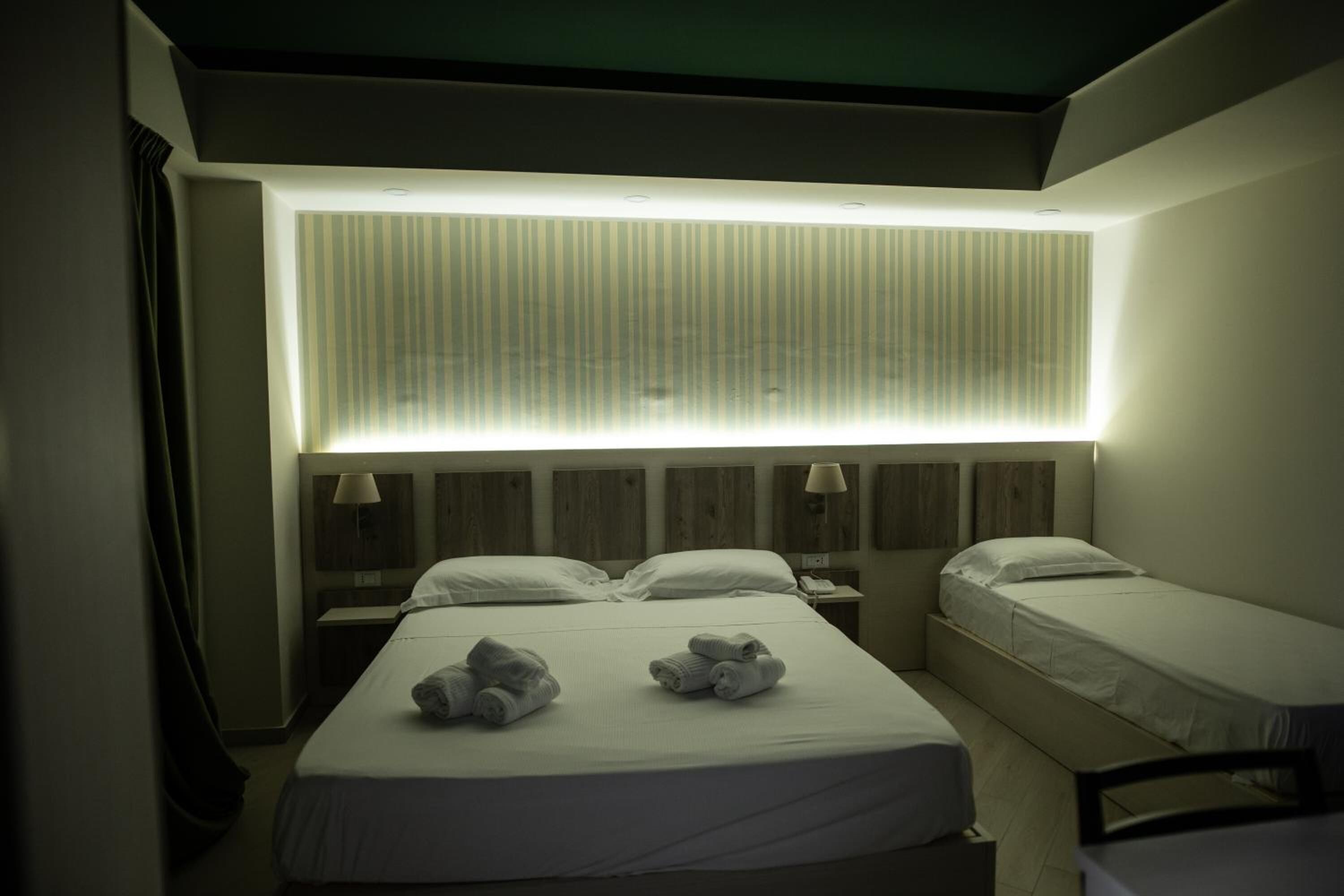 Una habitación de hotel con dos camas, un ventanal con persianas y una lámpara en el techo.