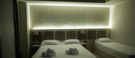 Una habitación de hotel con dos camas, un ventanal con persianas y una lámpara en el techo.
