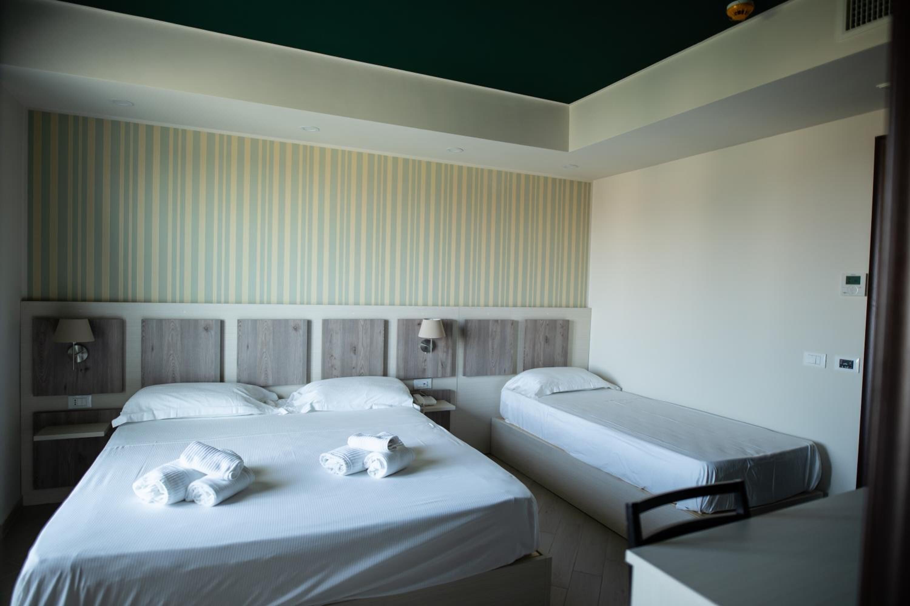 A hotel room with two single beds, a desk, and a chair.