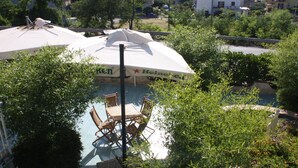 An outdoor pool area with a Heineken umbrella, surrounded by greenery and a statue. - Hotel Cliché (San Lucido)