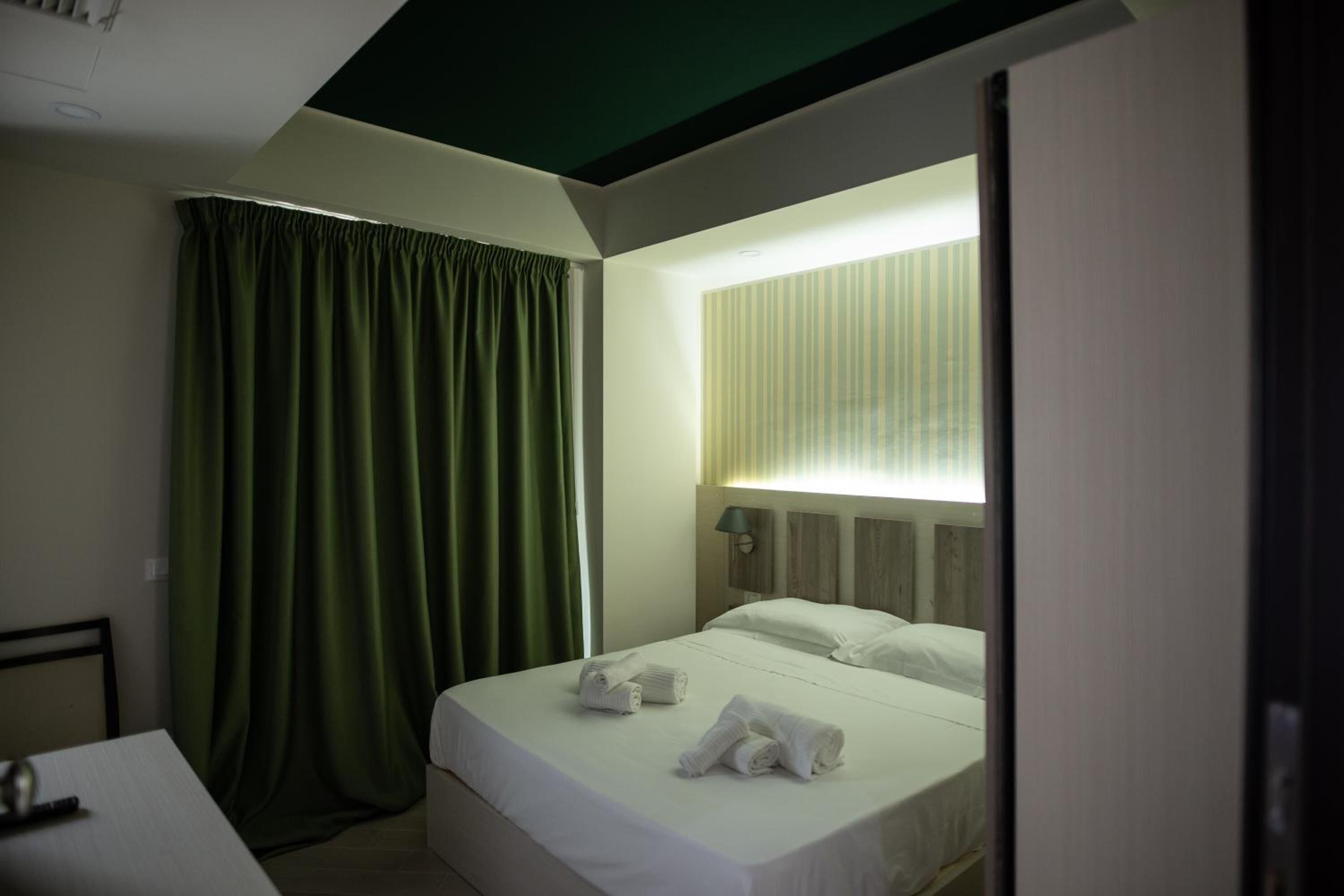 Habitación de hotel con cama, escritorio y ventana con cortinas.