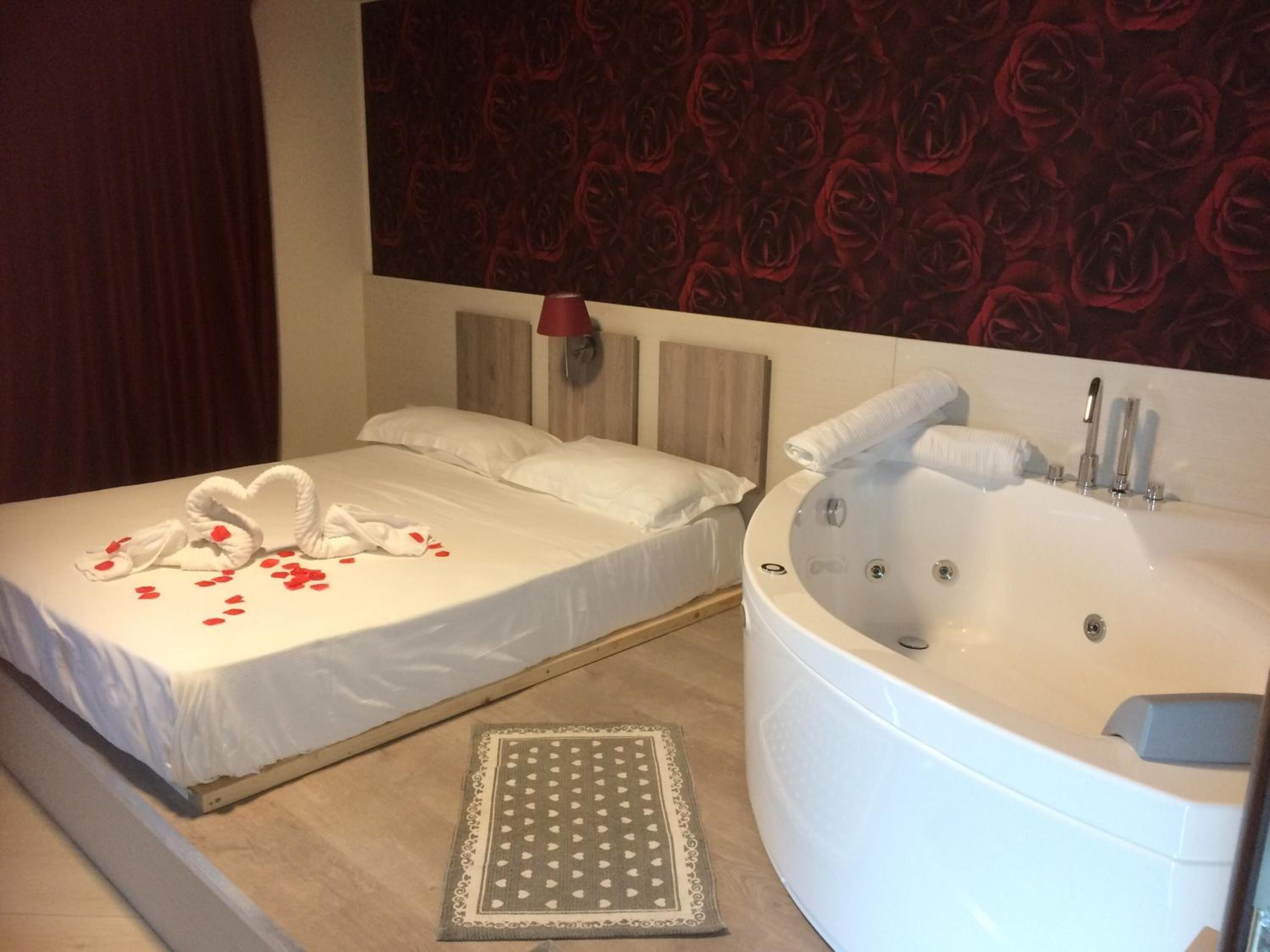 Une chambre d’hôtel avec un lit, une grande baignoire et un mur orné de motifs.