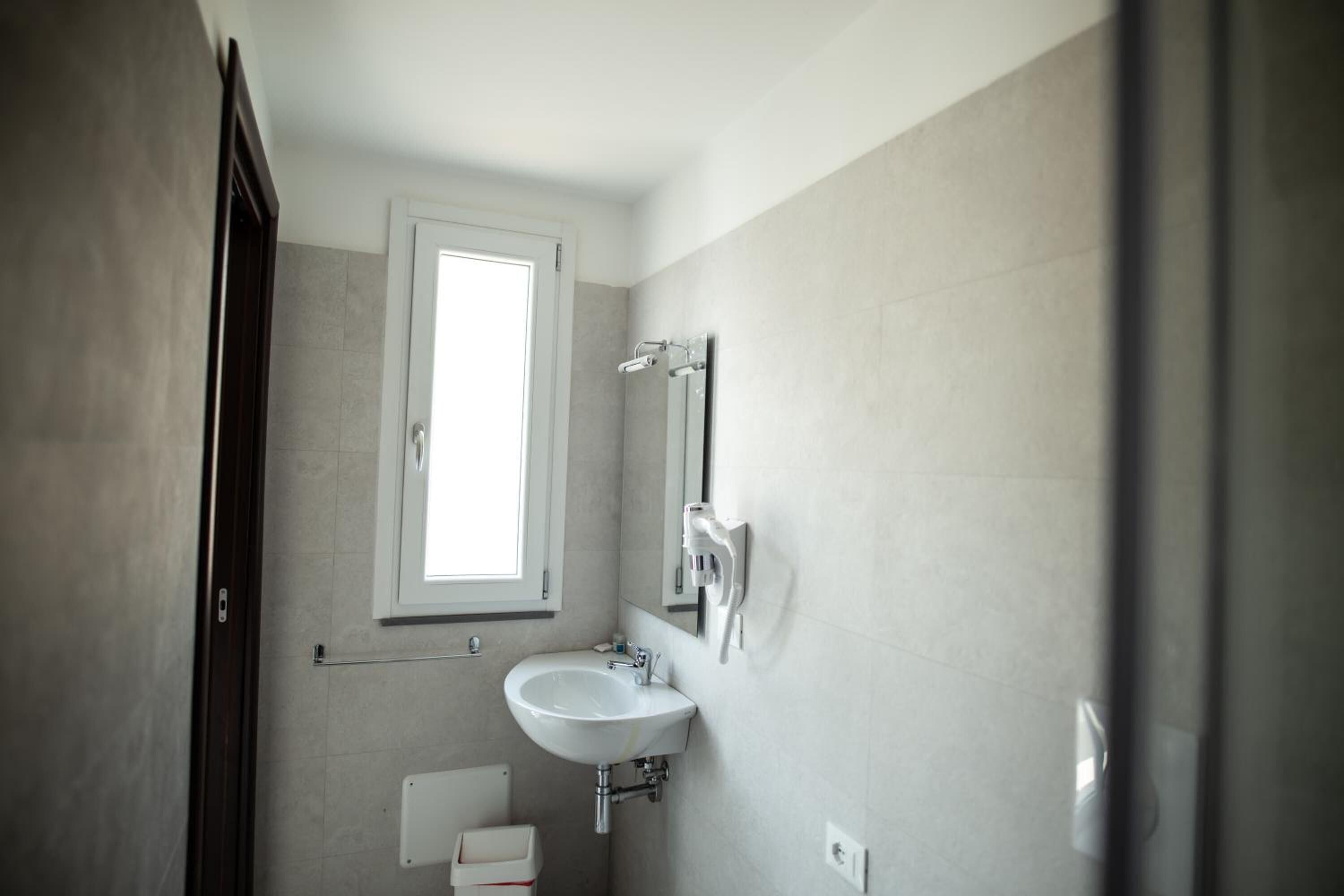 Une salle de bain avec une fenêtre, un lavabo et des toilettes.
