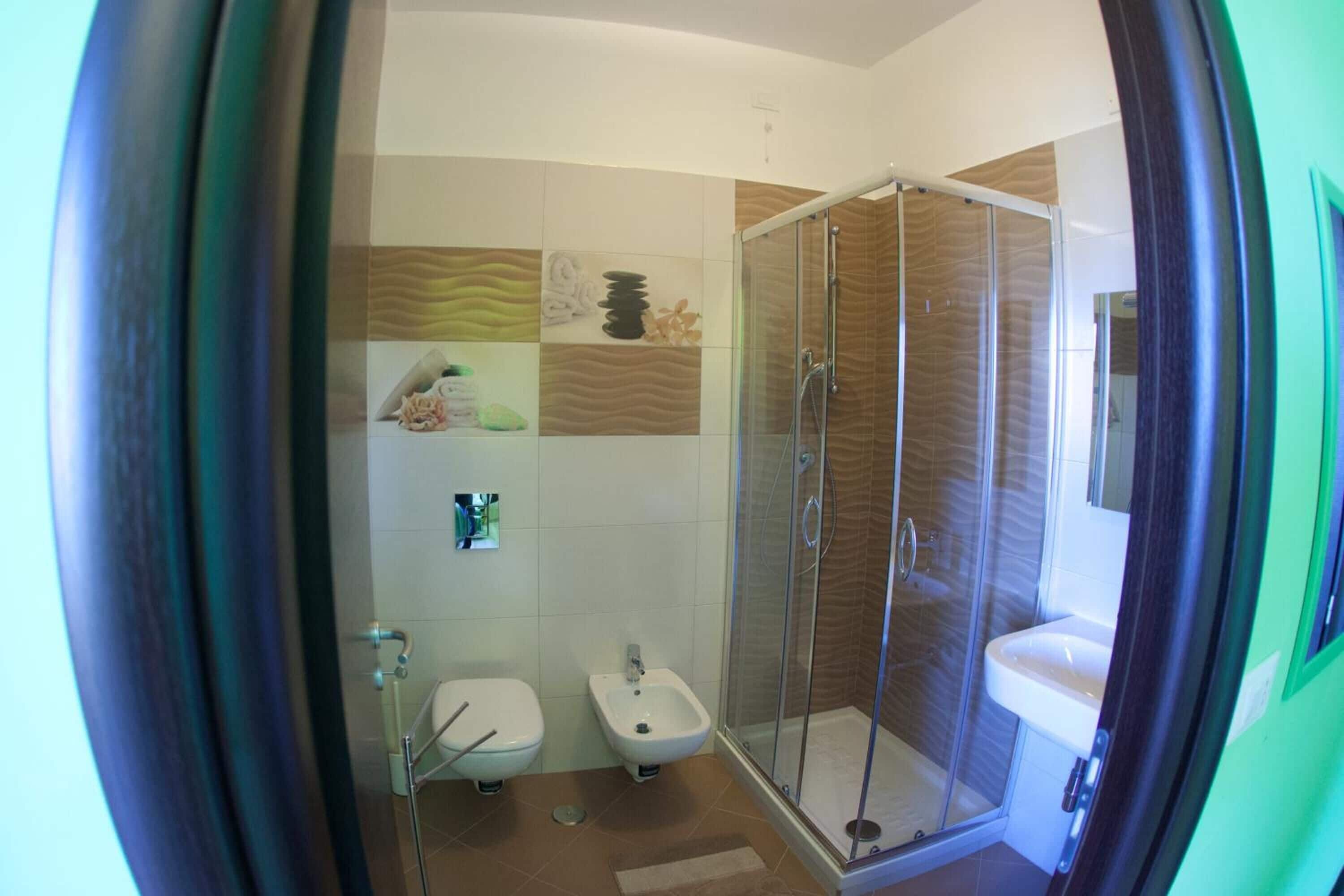 A bathroom with a shower, toilet, bidet, and sink.