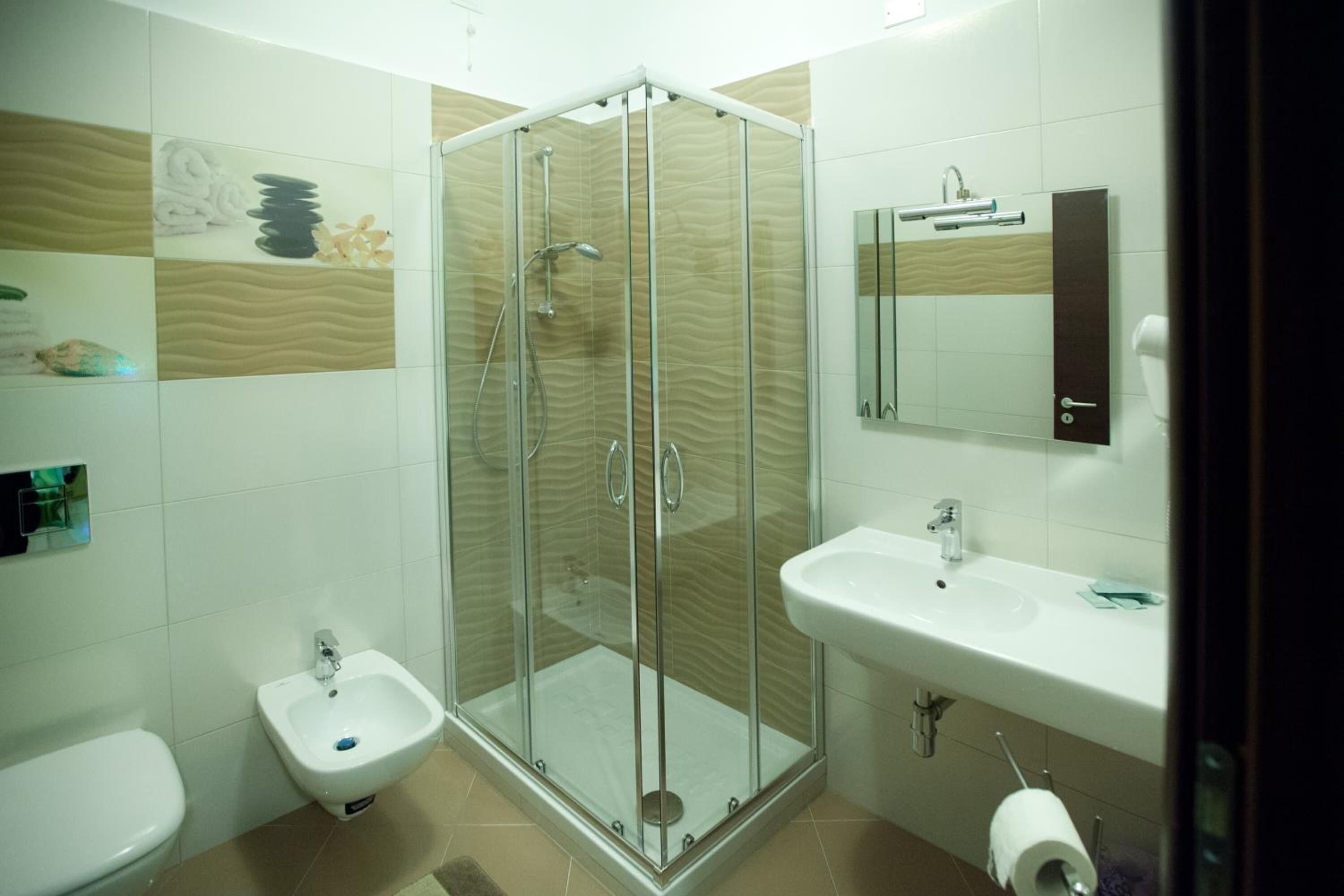 A modern bathroom with a glass-enclosed shower, a white sink, and a bidet.