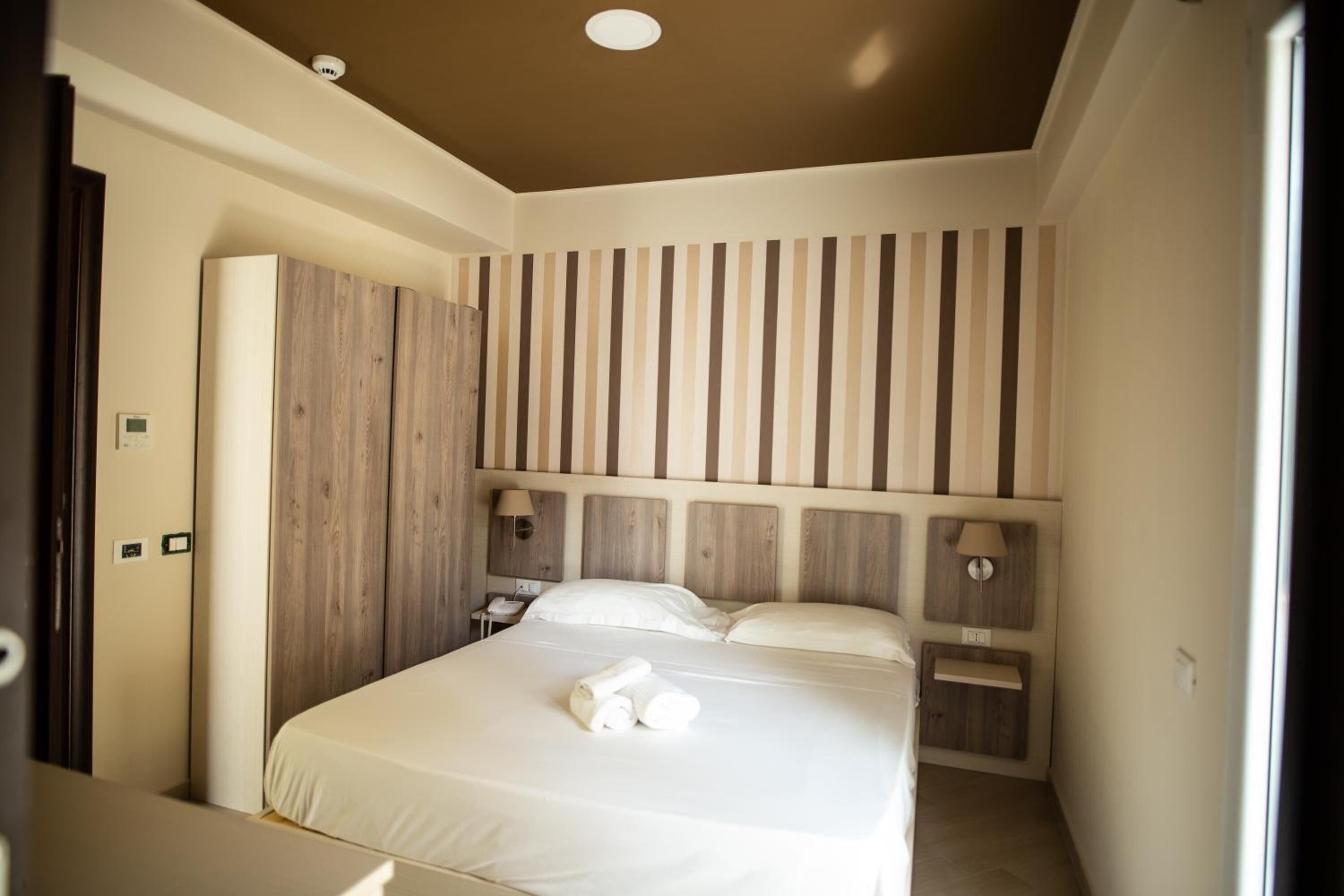 Une chambre à coucher avec un grand lit, une tête de lit en bois, des lampes de chevet et une armoire.