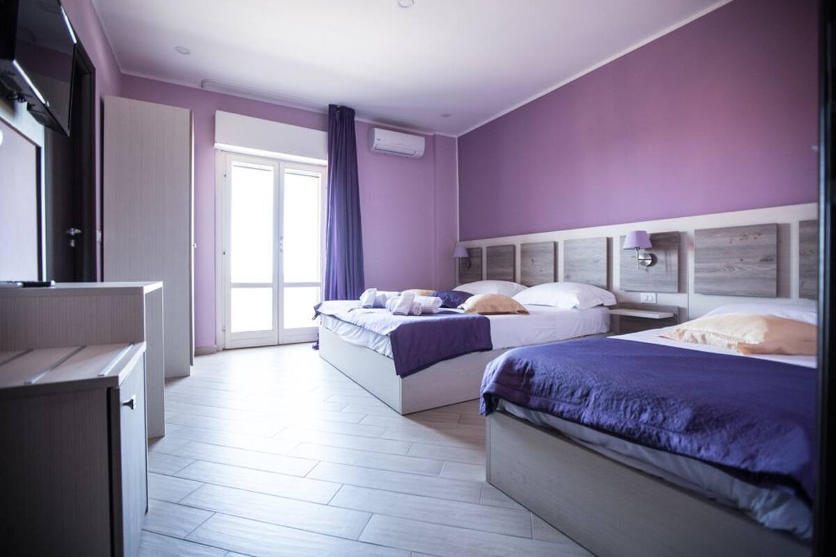 A bedroom with two beds, a wardrobe, and a desk.