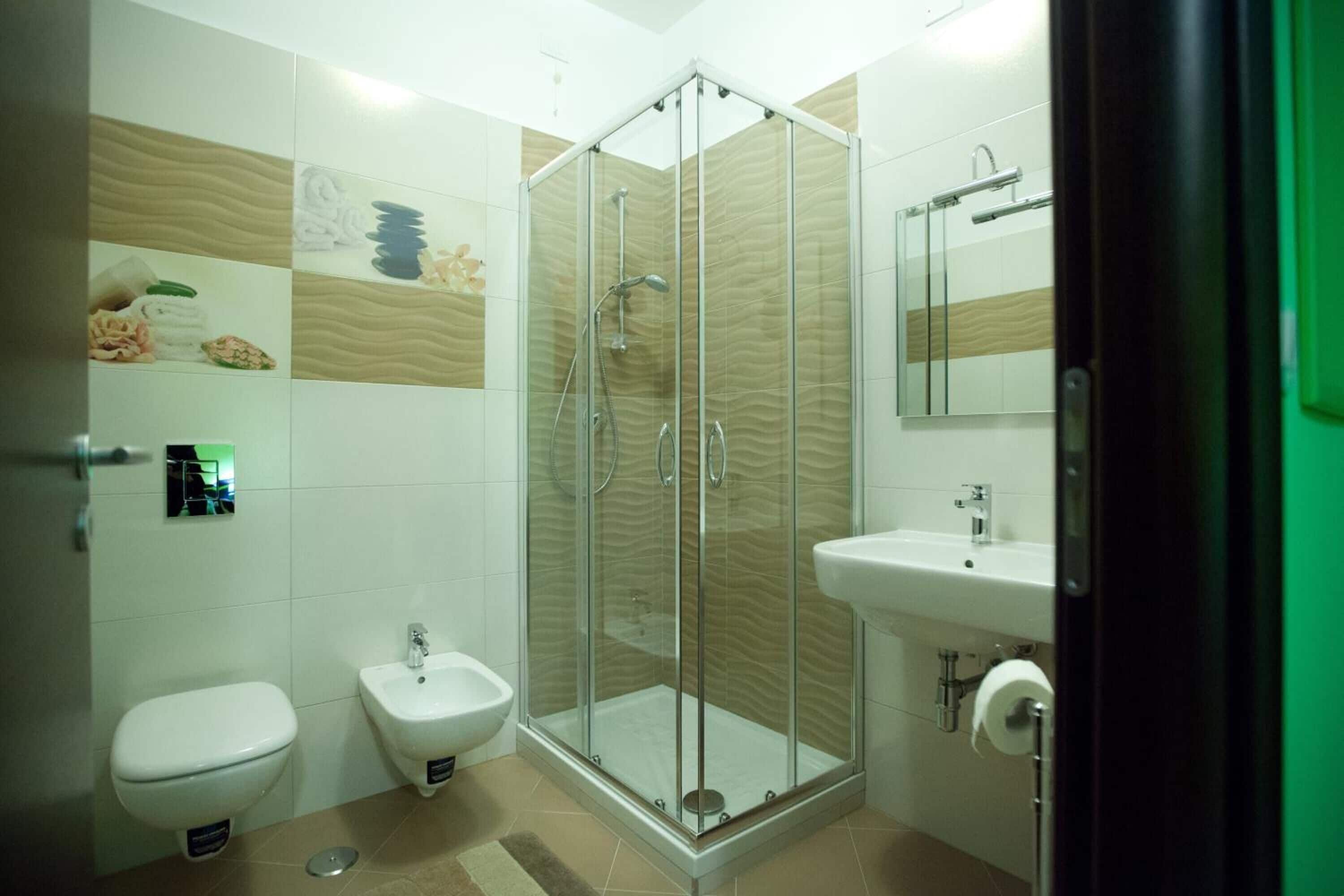 Un baño moderno con ducha de vidrio, un bidé, un inodoro y un lavamanos.