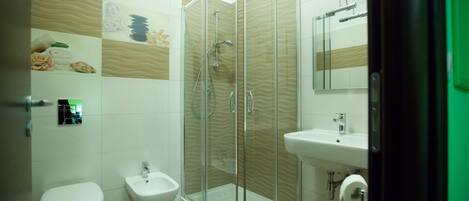 Un baño moderno con ducha de vidrio, un bidé, un inodoro y un lavamanos.
