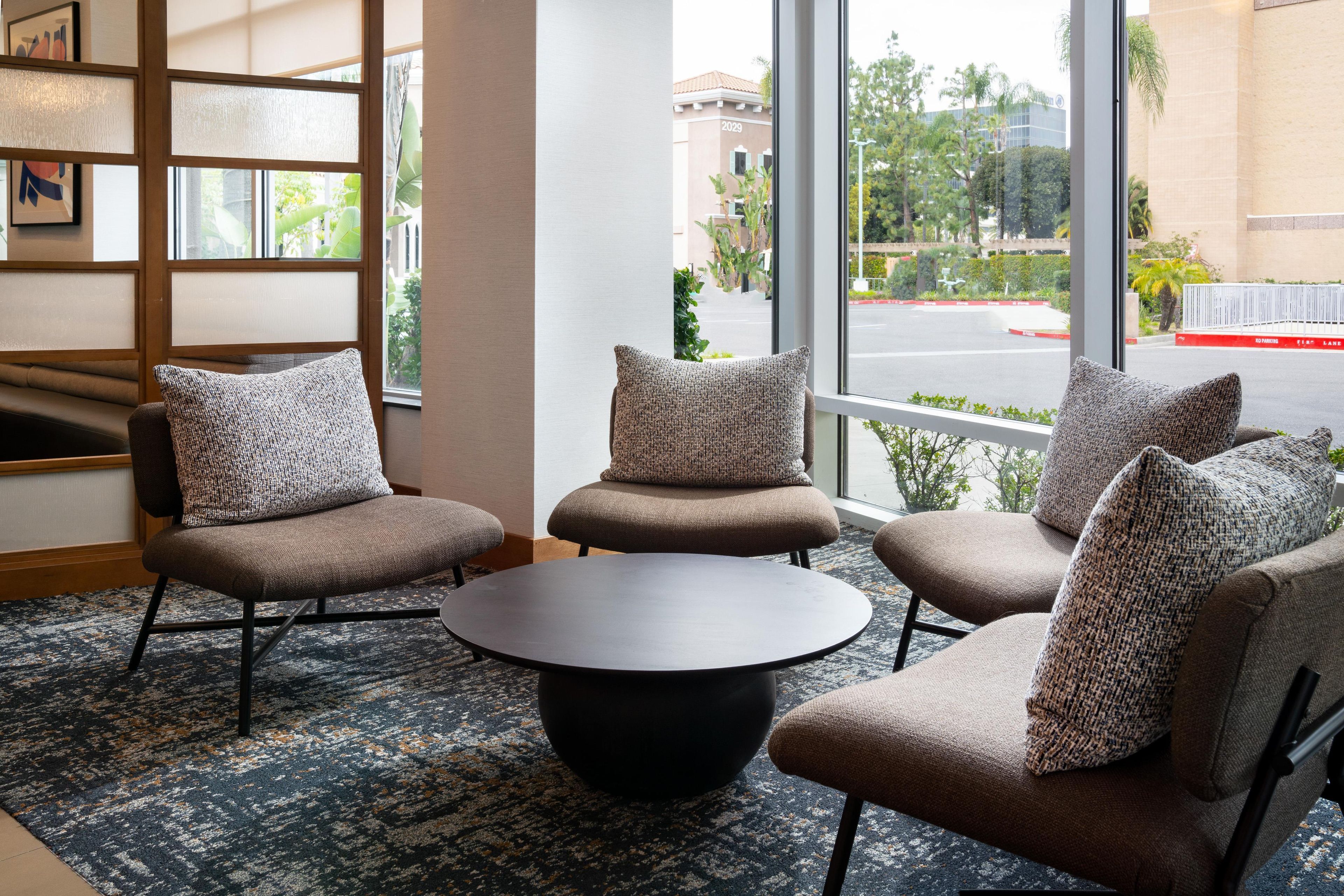 A seating area with a round table and four chairs, each with a patterned cushion.