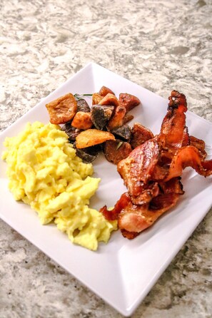 A square plate with scrambled eggs, roasted potatoes, and bacon. - Hyatt Place at Anaheim Resort/Convention Center (Anaheim)