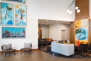 Un hall d’hôtel moderne, doté d’un espace salon, d’œuvres d’art aux murs et d’une vue sur la salle à manger.