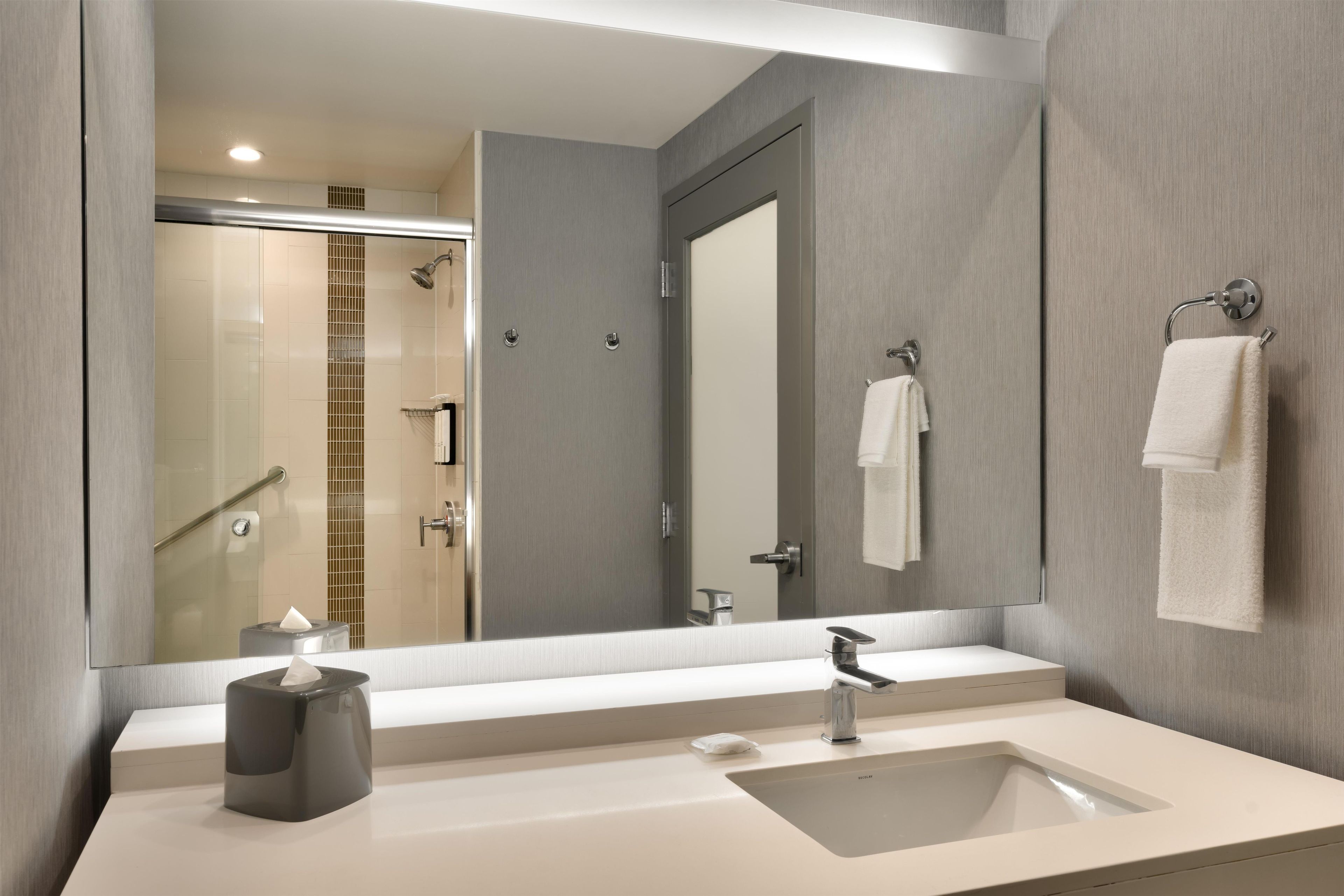 Un baño moderno con un espejo grande, un lavabo y una zona de ducha.
