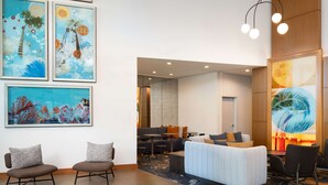 Un hall d’hôtel moderne avec un espace salon, des œuvres d’art aux murs et une grande fenêtre.