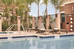 Zona de piscina con sillones de descanso y un perchero para toallas.