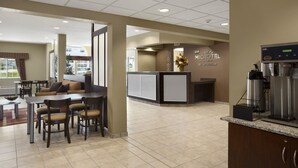 Un vestíbulo de hotel con mostrador de recepción, zona de estar y estación de café.