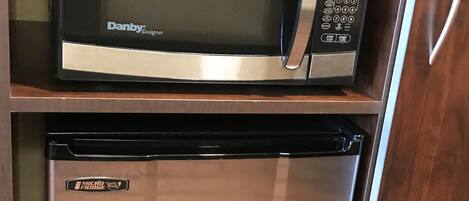 A microwave and a refrigerator in a kitchen cabinet.