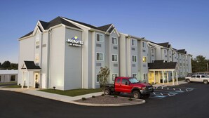 Un microhotel de diseño moderno, con un estacionamiento y una camioneta roja estacionada al frente.