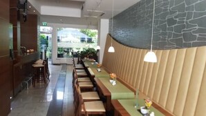 A modern restaurant with a long counter, wooden stools, and pendant lighting. - Hotel Arena City (Leipzig)