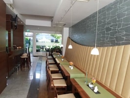 Un restaurante moderno con una barra alargada, taburetes de madera e iluminación colgante.