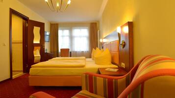 Une chambre d’hôtel avec un lit, un canapé, une télévision et un lustre.