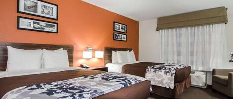 A hotel room with two beds, a desk, and a chair. There are framed pictures on the wall.
