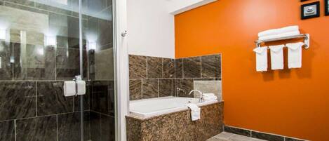 A modern bathroom with a glass-enclosed shower, a freestanding bathtub, and an orange accent wall.