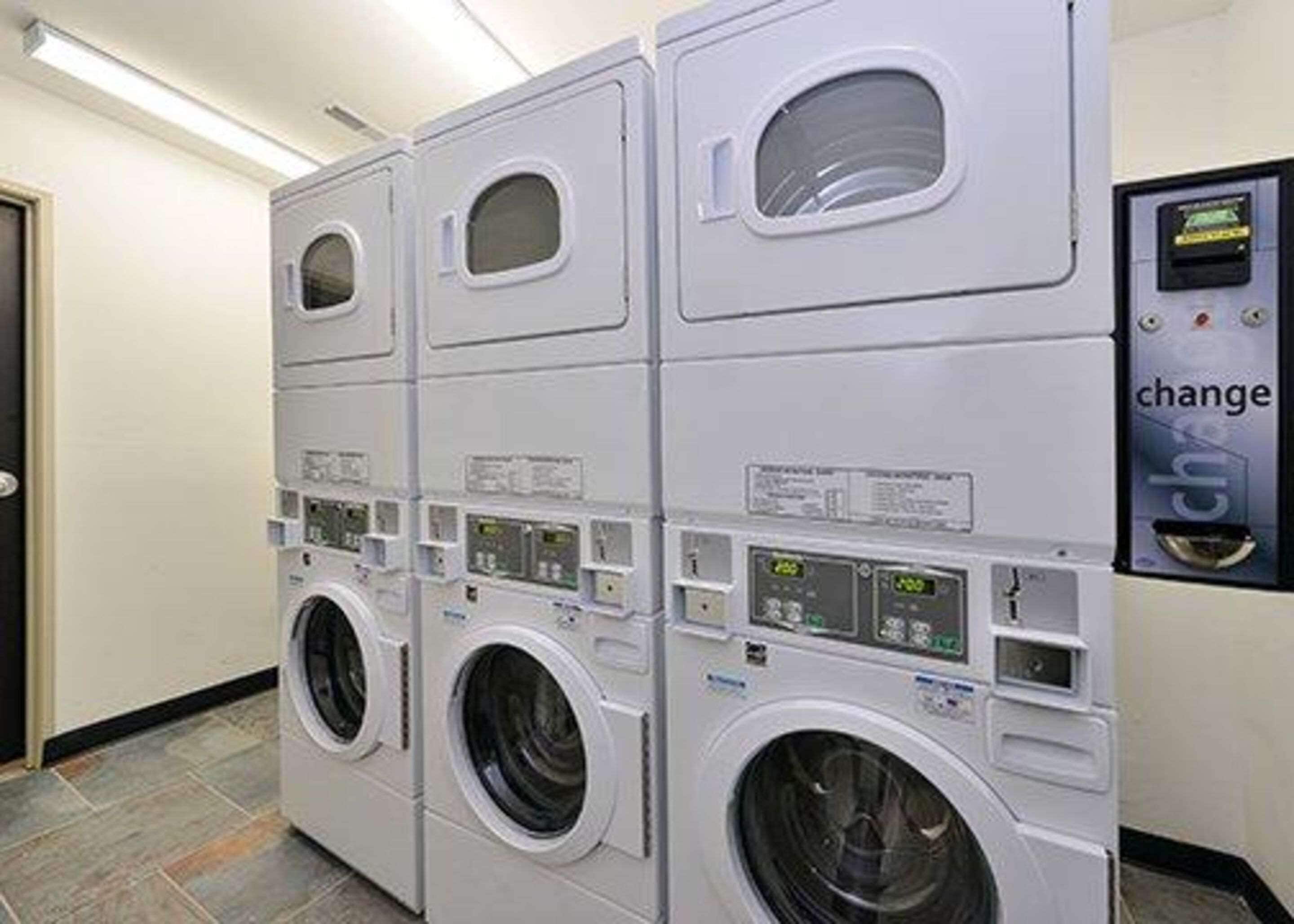 A row of stacked front-loading washing machines with control panels and a change machine.