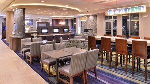 A hotel lobby with a seating area, a reception desk, and a TV screen.