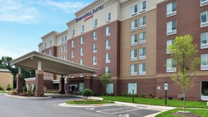 A hotel with a brick facade, a covered entrance, and a parking lot.