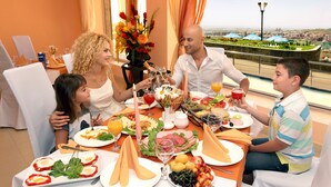 A dining table with food, drinks, and a city view. - Panorama Resort (Yerevan)