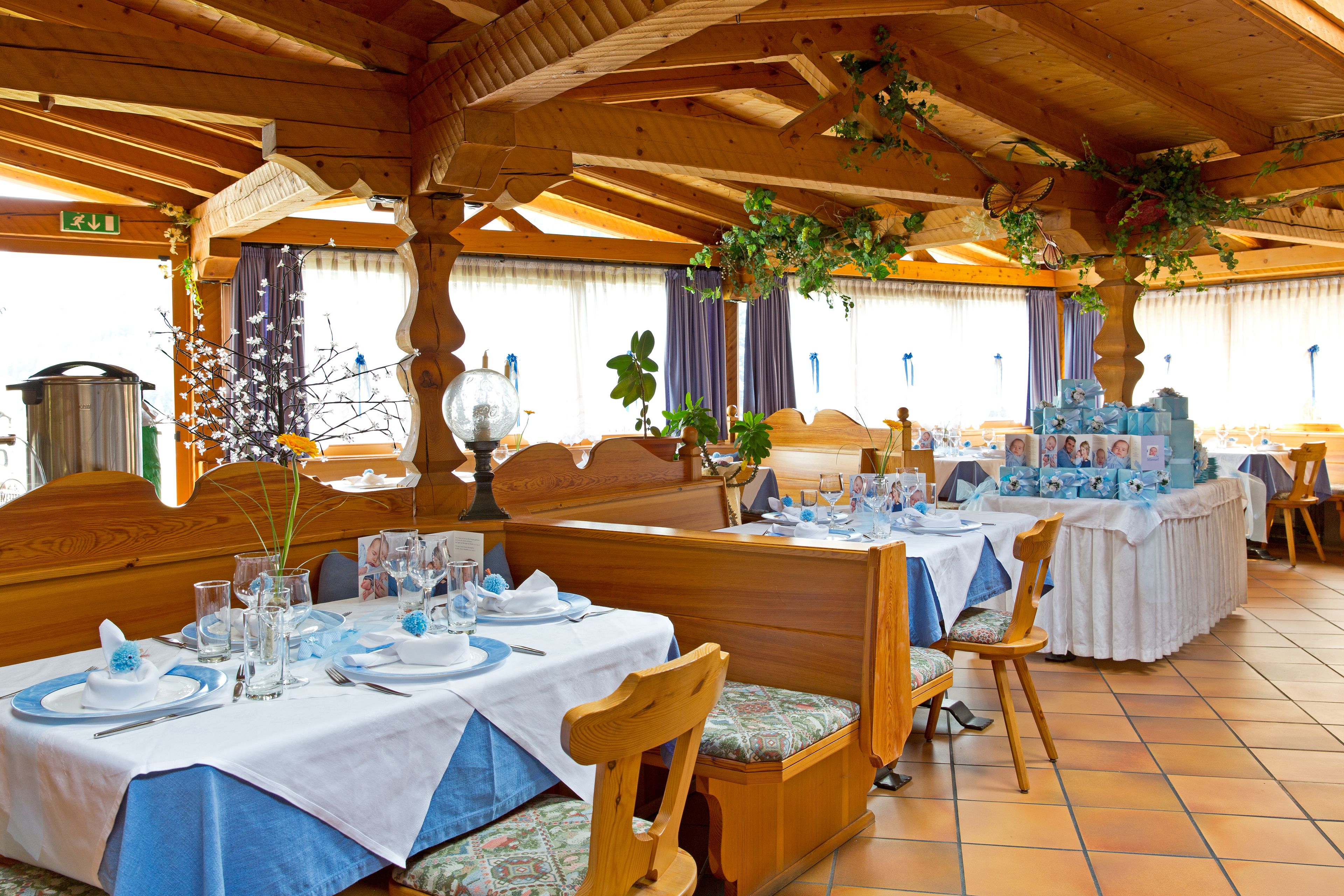 A restaurant with wooden interiors, tables set with blue and white tablecloths, and a variety of dishes and drinks.
